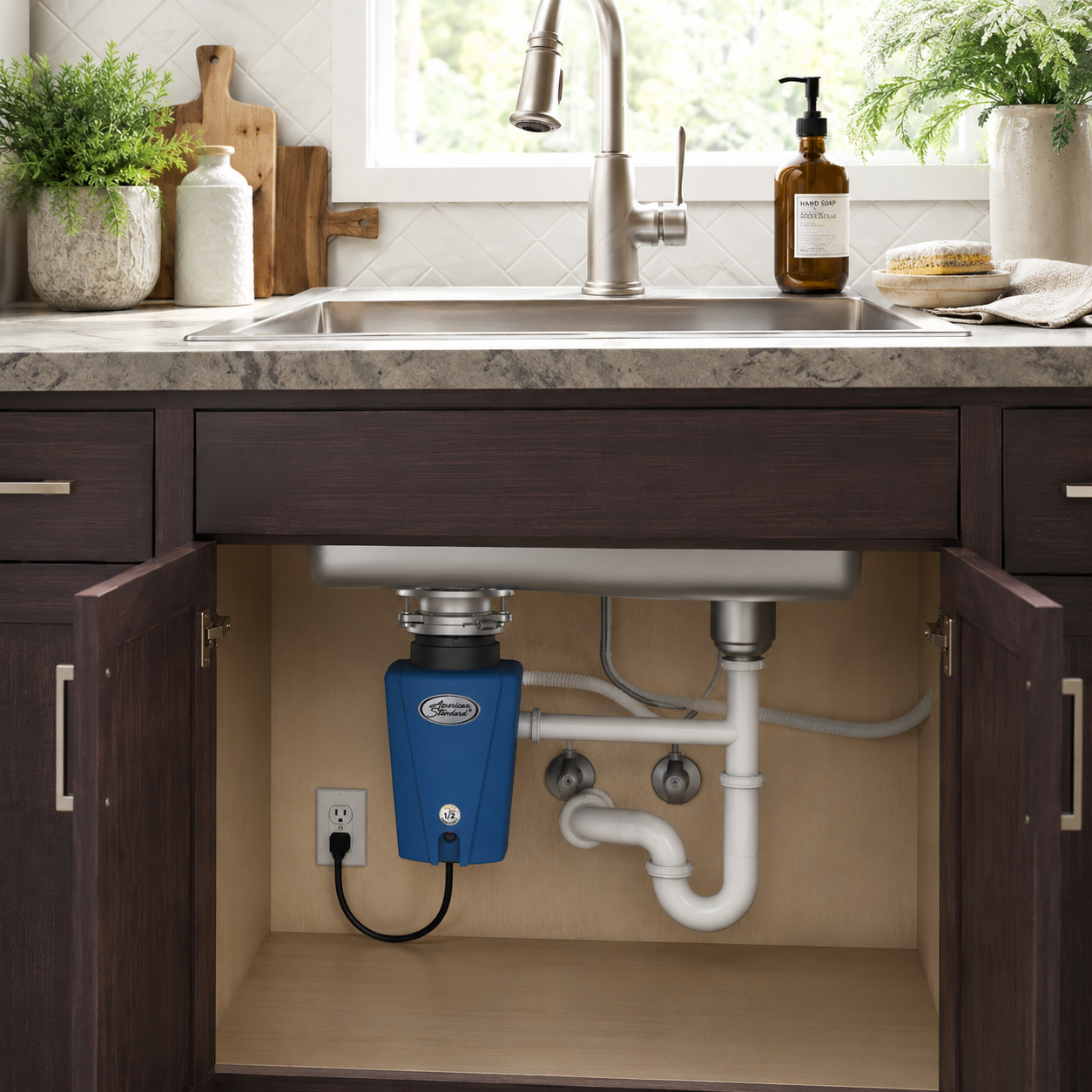 Blue disposer installed under a kitchen sink with visible pipes and an electrical outlet.
